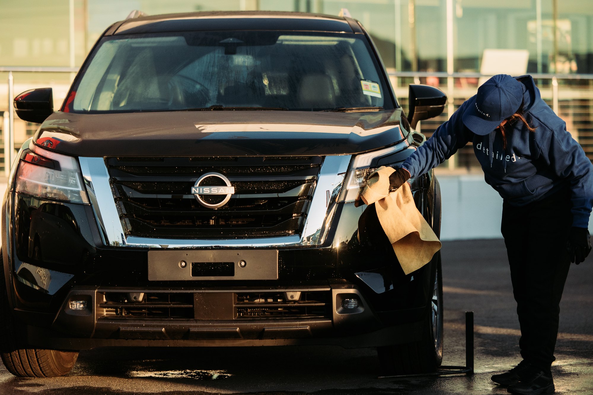 A Detailed team member detailing a clean new Nissan at golden hour